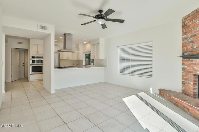 unfurnished living room featuring ceiling fan, sink, light tile patterned floors, and a fireplace