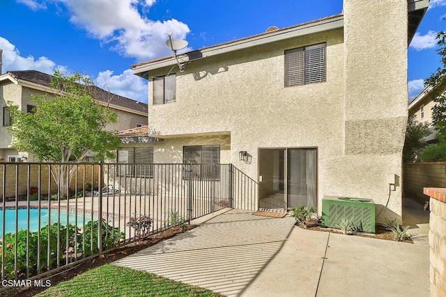 rear view of house with a fenced in pool, a patio, and central air condition unit