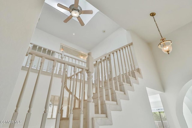 stairway featuring a towering ceiling and ceiling fan