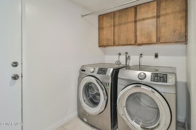 washroom featuring separate washer and dryer, light tile patterned floors, and cabinets