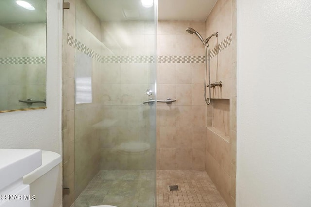 bathroom featuring toilet and a tile shower