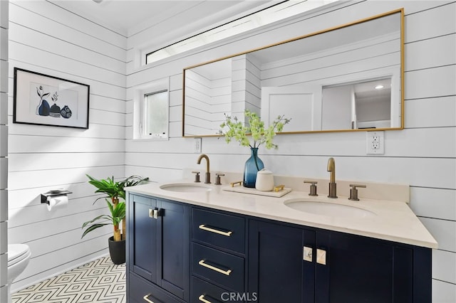 bathroom with vanity, wood walls, and toilet