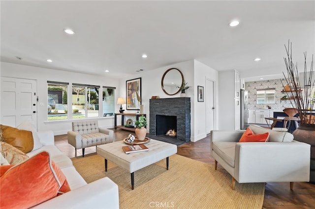 living room with light parquet flooring and a stone fireplace