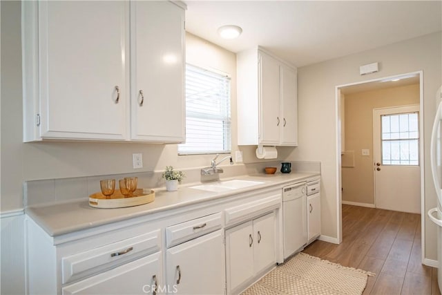 kitchen featuring a healthy amount of sunlight, white dishwasher, sink, and white cabinets