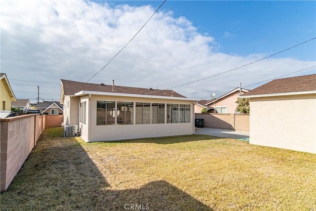 rear view of property featuring central AC, a sunroom, and a lawn