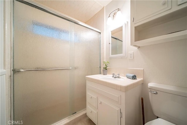 bathroom featuring a shower with door, vanity, and toilet