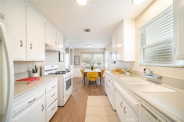 kitchen featuring white cabinetry, white appliances, sink, and light hardwood / wood-style flooring