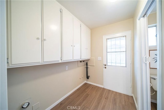 clothes washing area with washer hookup, light hardwood / wood-style floors, and cabinets