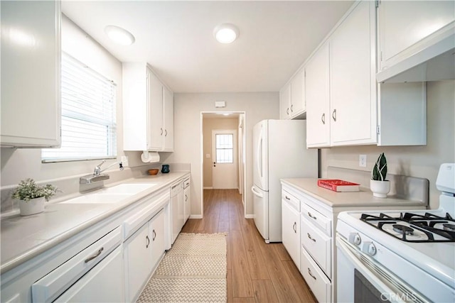 kitchen featuring white cabinetry, white appliances, sink, and light hardwood / wood-style flooring