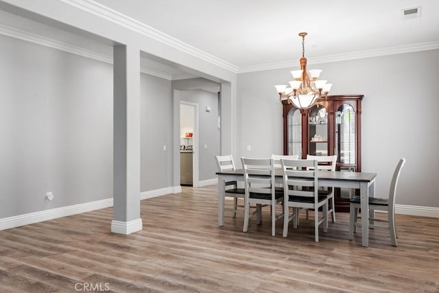 dining room featuring ornamental molding, light hardwood / wood-style flooring, and a notable chandelier