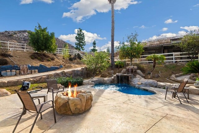 view of swimming pool featuring a mountain view, a patio area, and a fire pit