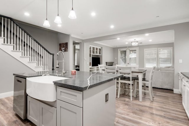 kitchen featuring decorative light fixtures, white cabinetry, sink, a kitchen island with sink, and stainless steel dishwasher