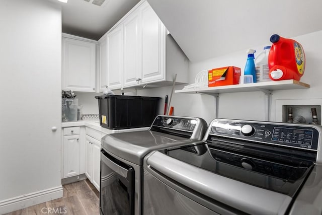 laundry room featuring cabinets, dark hardwood / wood-style floors, and washer and clothes dryer