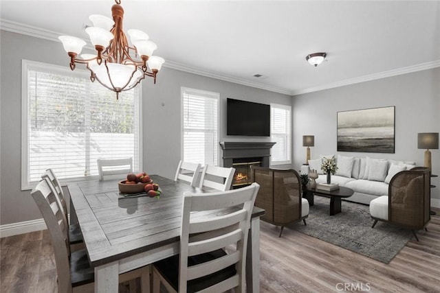 dining area with hardwood / wood-style flooring, ornamental molding, and a chandelier