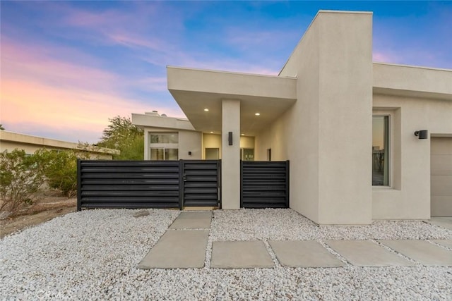 gate at dusk featuring a garage