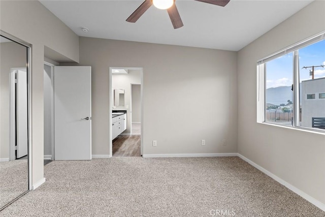 unfurnished bedroom with ceiling fan, connected bathroom, a mountain view, and carpet floors