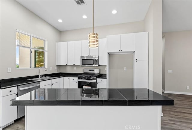 kitchen with stainless steel appliances, sink, a kitchen island, and white cabinets