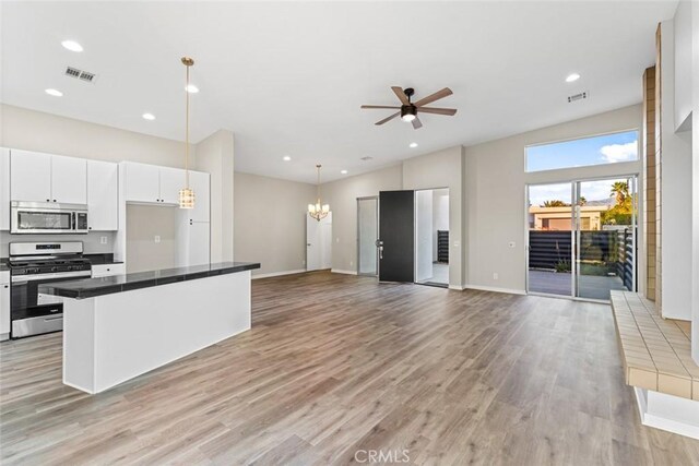 kitchen with ceiling fan with notable chandelier, white cabinetry, hanging light fixtures, stainless steel appliances, and light hardwood / wood-style flooring