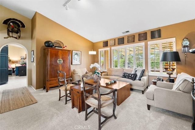 living room with track lighting, high vaulted ceiling, and light carpet