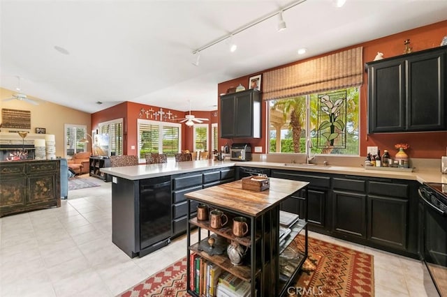 kitchen with ceiling fan, range, sink, and a kitchen island