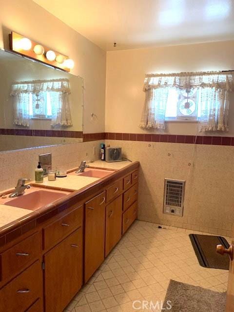 bathroom featuring heating unit, plenty of natural light, tile walls, and vanity