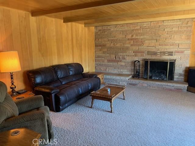 living room with wood ceiling, a fireplace, beamed ceiling, and wood walls