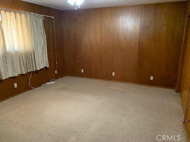 spare room with light carpet and wood walls