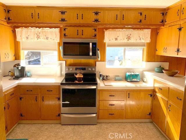 14650 Pearl Ave, Clearlake, CA 95422 - kitchen featuring stainless steel appliances, light countertops, and brown cabinetry