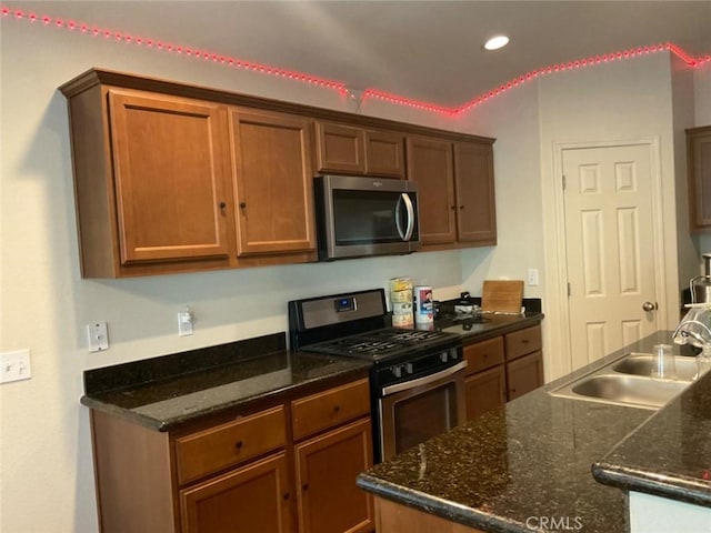 kitchen featuring appliances with stainless steel finishes, sink, and dark stone counters