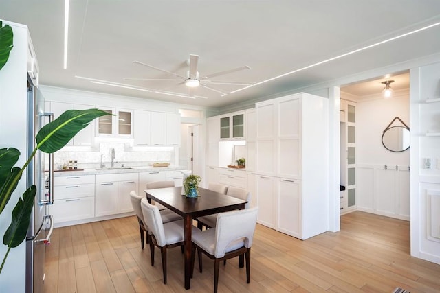 dining space with ceiling fan, ornamental molding, sink, and light wood-type flooring