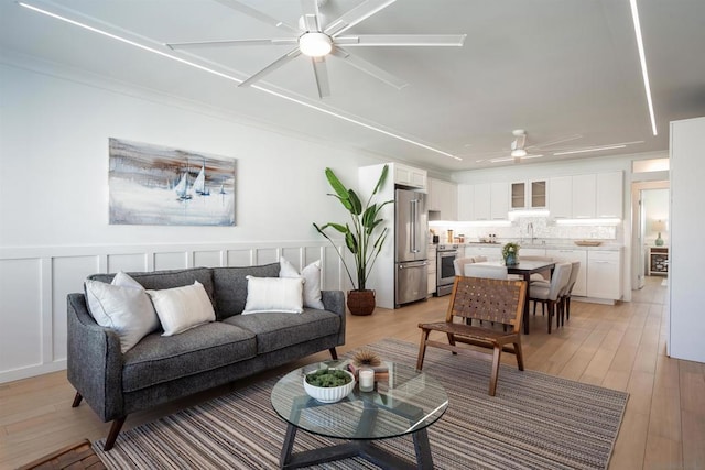 living room featuring sink, light hardwood / wood-style floors, and ceiling fan