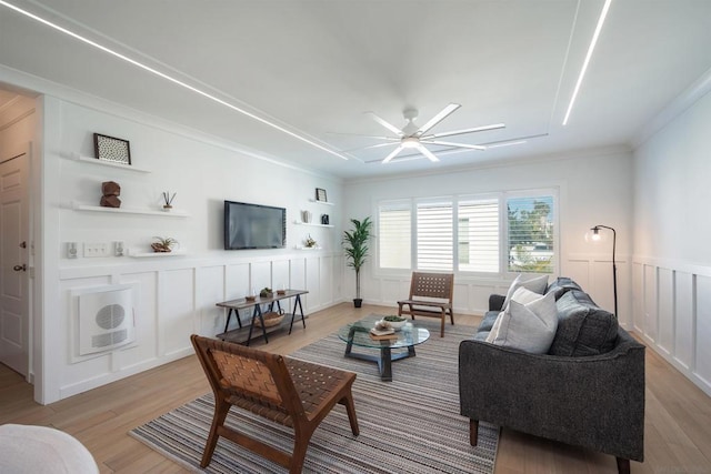 living room featuring ornamental molding, light hardwood / wood-style floors, and ceiling fan