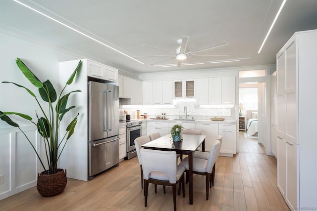 kitchen with appliances with stainless steel finishes, tasteful backsplash, white cabinetry, sink, and light wood-type flooring