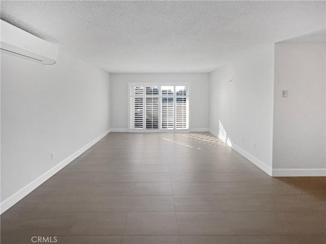 unfurnished room featuring a textured ceiling and an AC wall unit