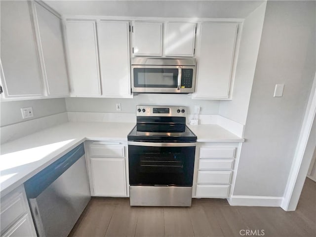 kitchen with stainless steel appliances, white cabinets, and light hardwood / wood-style floors