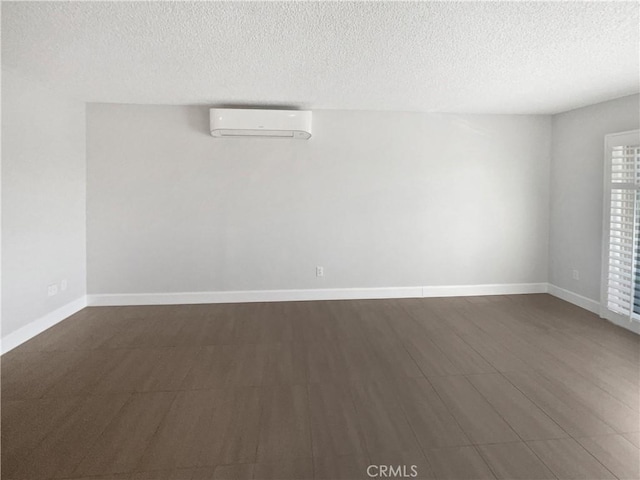 unfurnished room featuring a wall mounted AC, a textured ceiling, and dark hardwood / wood-style flooring