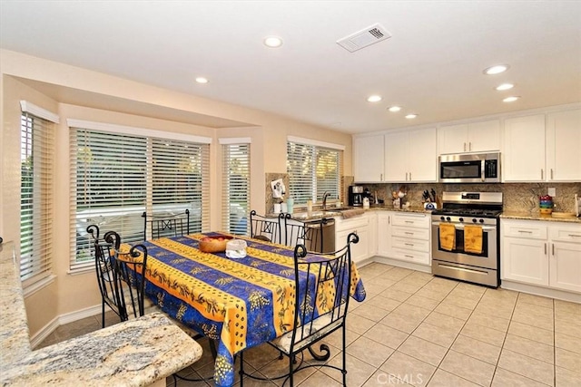 kitchen featuring white cabinetry, backsplash, and appliances with stainless steel finishes