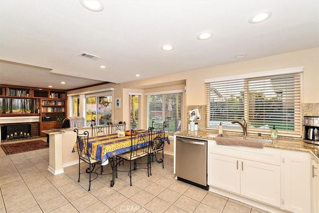 kitchen featuring dishwasher, sink, light tile patterned floors, and white cabinets