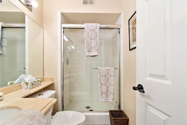 bathroom with vanity, toilet, and a shower with door