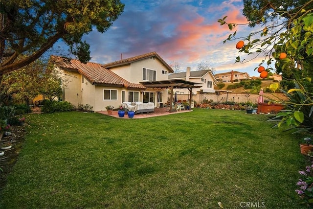 back house at dusk with a yard, a patio area, and a pergola