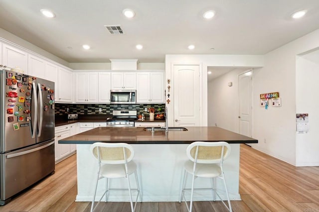 kitchen with a breakfast bar, sink, white cabinetry, a center island with sink, and stainless steel appliances