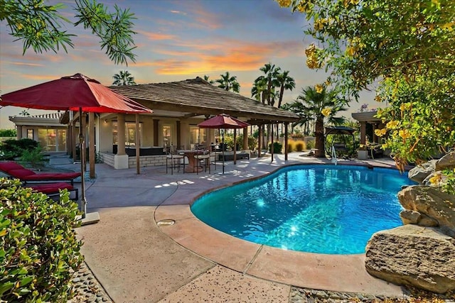 pool at dusk with a patio area