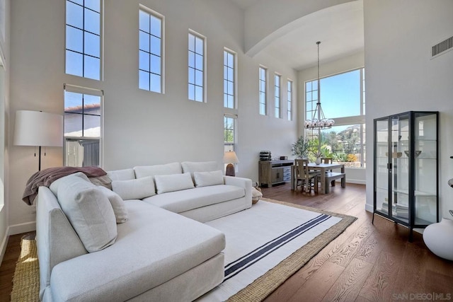 living room with dark hardwood / wood-style flooring, a high ceiling, and an inviting chandelier