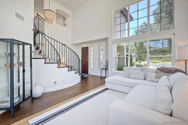 living room with dark hardwood / wood-style flooring, a notable chandelier, and a towering ceiling