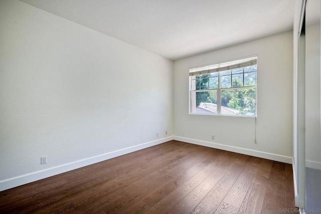 unfurnished room with dark hardwood / wood-style flooring