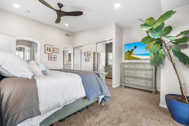 carpeted bedroom featuring ensuite bathroom, ceiling fan, and a closet