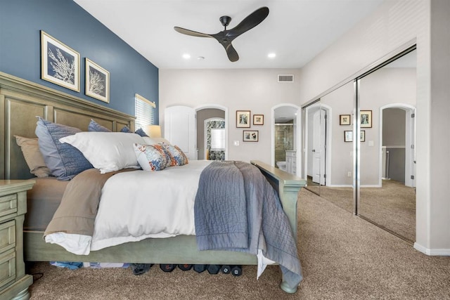 bedroom with ensuite bathroom, carpet, ceiling fan, and a closet