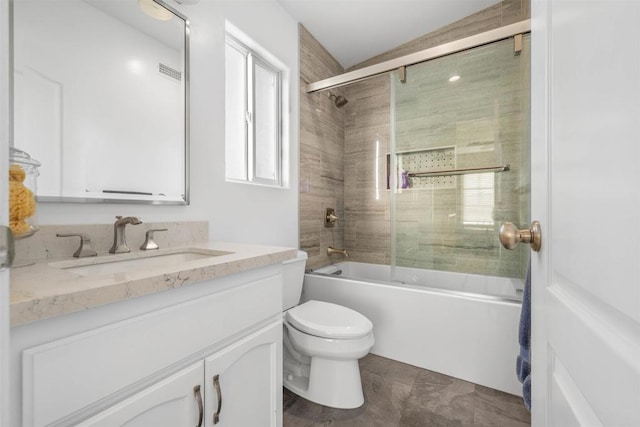 full bathroom with vanity, bath / shower combo with glass door, and toilet