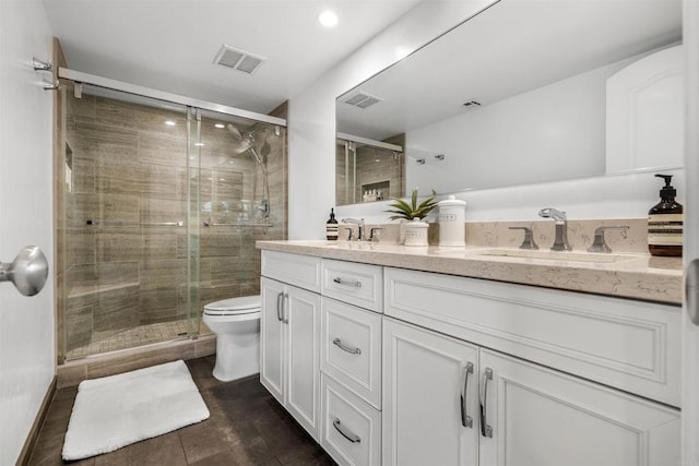 bathroom featuring a shower with door, vanity, and toilet