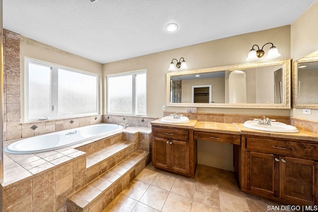 bathroom with vanity, tiled tub, and tile patterned flooring